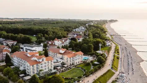 Beleuchtetes großes Gebäude am Strand mit Wasser im Vordergrund.