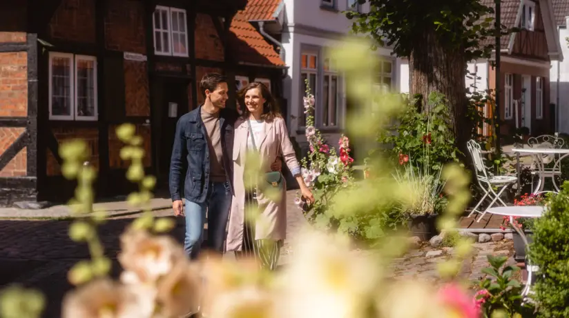 Ein Paar spaziert lächelnd durch die Altstadt Lübeck.