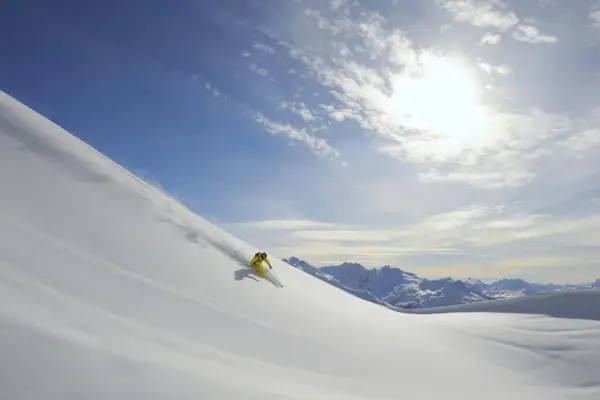 Eine Person fährt auf Skiern einen verschneiten Hang hinunter.