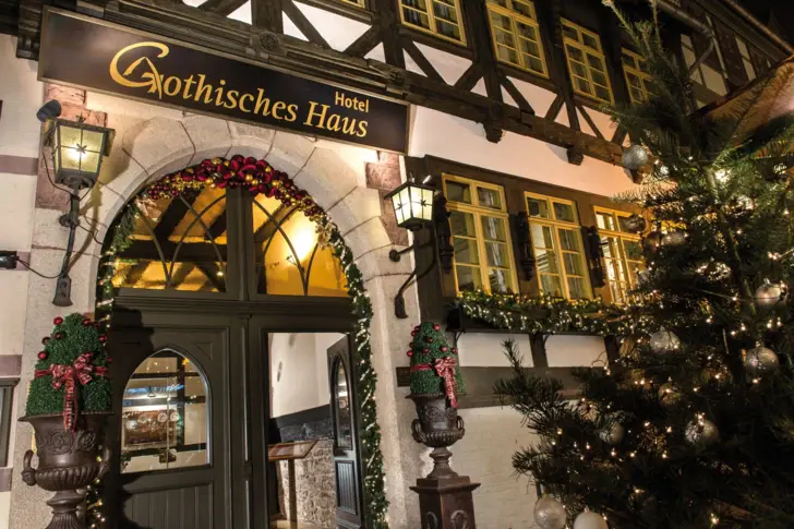 A-ROSA Gothisches Haus Wernigerode von außen mit Weihnachtsdekoration rund um den Eingangsbereich und einem Weihnachtsbaum.