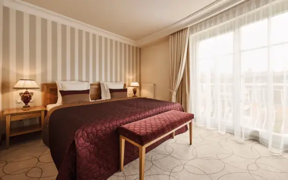 Ein Bett mit einer Bank in einem Zimmer mit gestreiften Wänden.