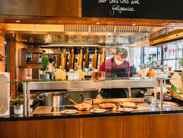 Persona con mascherina dietro al bancone in un ristorante fast food.