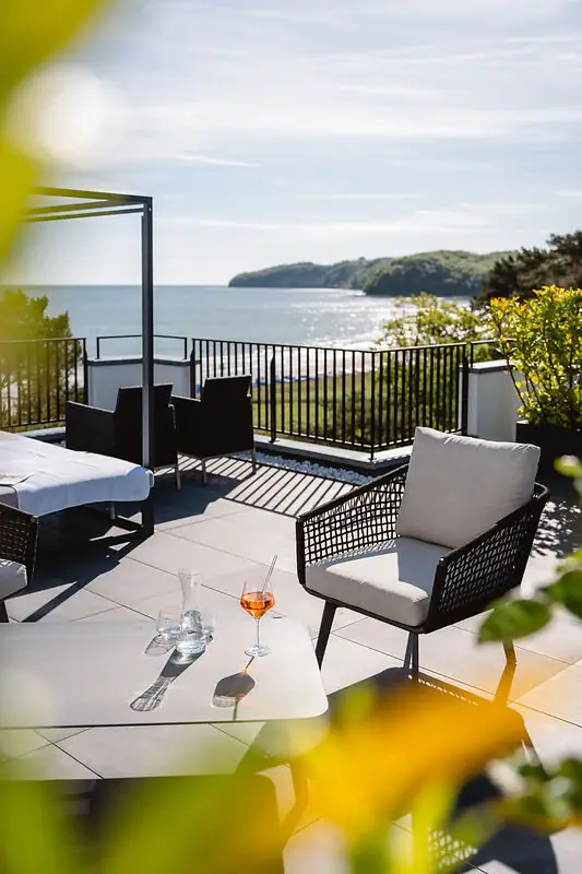 Ein Tisch und Stühle auf einer Terrasse mit Blick auf ein Gewässer.
