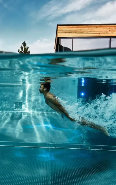 Mann schwimmt unter Wasser in einem Außenpool