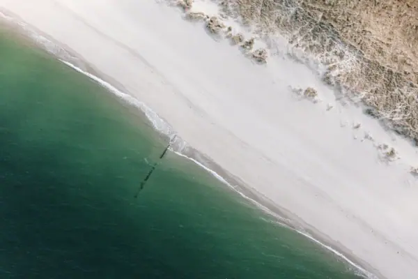 Ein schöner Strand auf Sylt mit Sand und Wasser aus der Vogelperspektive.