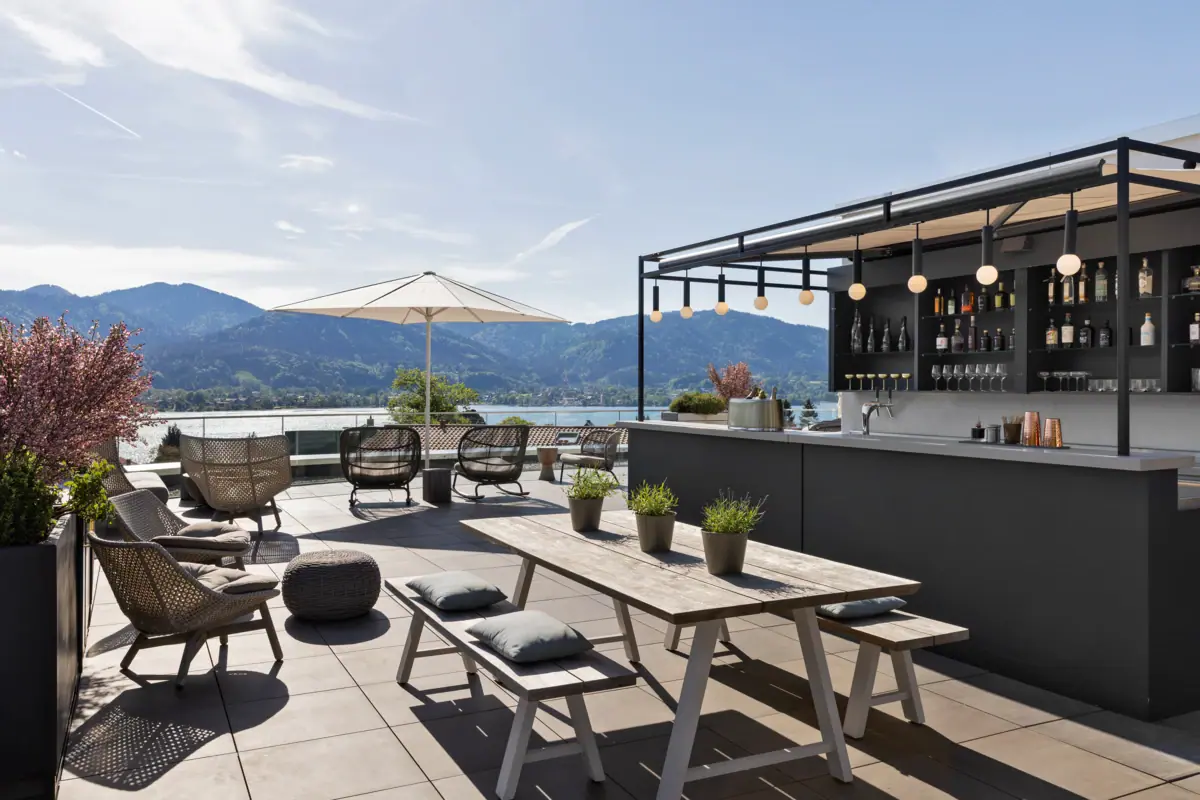 Roof Top Bar Rooftop-Terrasse mit Bar, Stühlen, Tisch und Sonnenschirm.