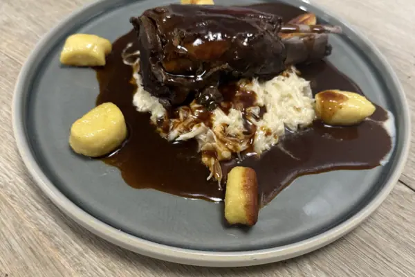 Haxe vom Wildschwein Ein Teller mit einem Gericht auf einem Tisch.