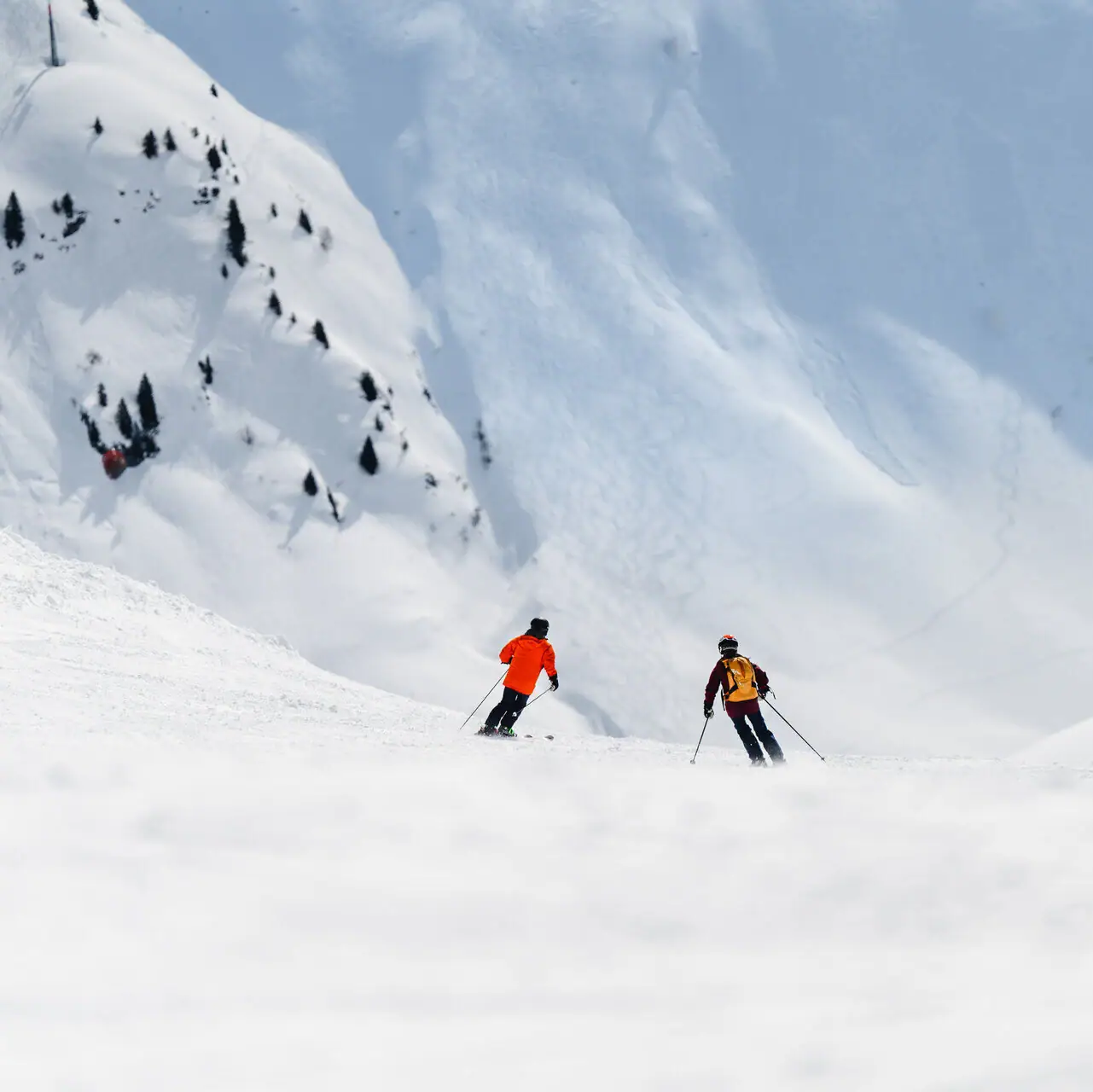 Eine Gruppe von Menschen fährt auf Skiern einen verschneiten Berg hinunter.