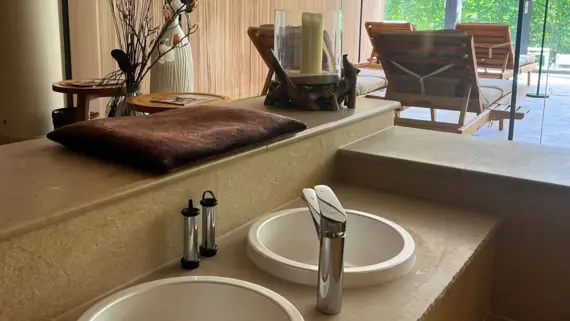 Ein Fußbecken im Wellnessbereich mit Liegen und Deko im Hintergrund. 