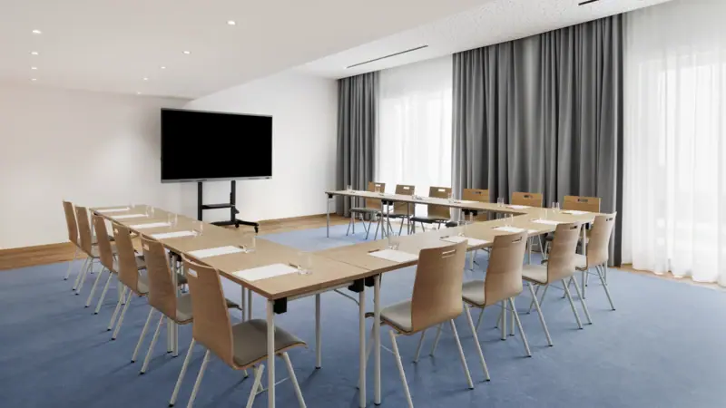 Das A-ROSA Tegernsee als Tagungshotel mit einem Konferenzraum mit einigen Tischen und Stühlen.