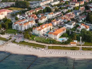 Luftaufnahme von einem Strand mit angrenzenden Gebäuden und Bäumen.