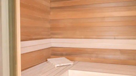 Wooden bench in a wooden sauna with wooden headboard.