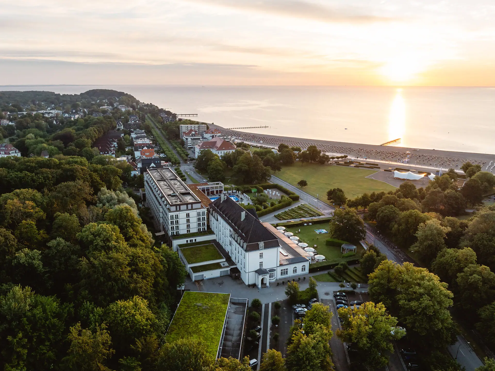 A-ROSA Travemünde Luftaufnahme einer Stadt mit Bäumen und einem Gewässer.
