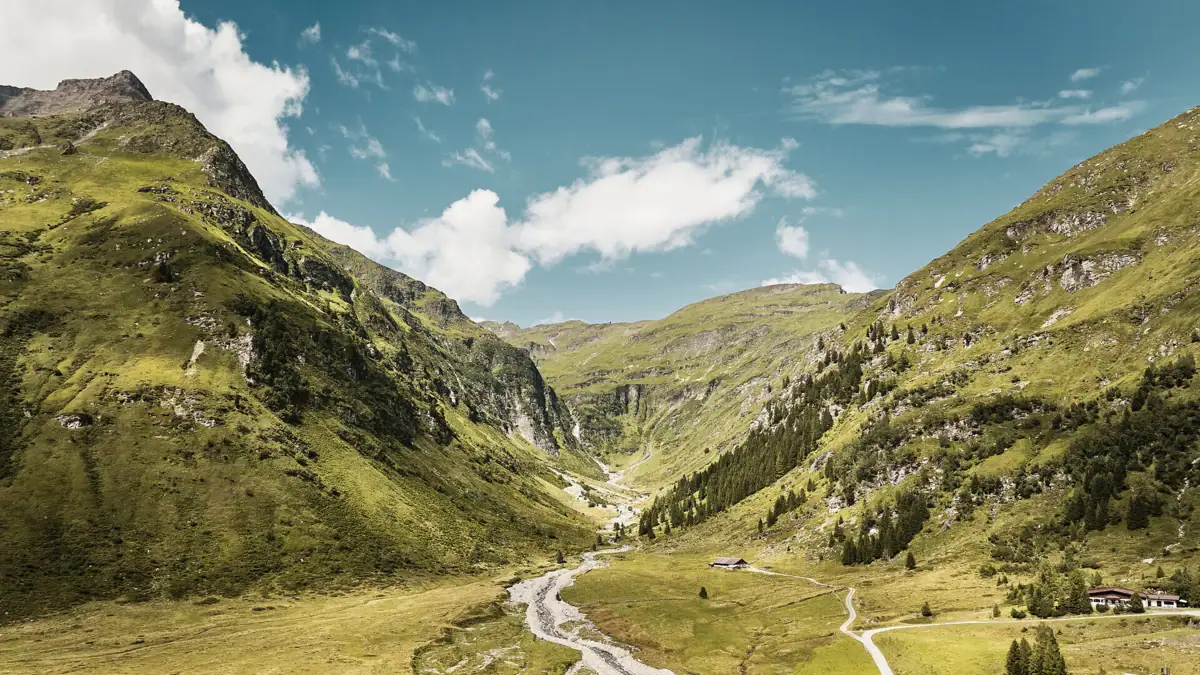 Ein Wanderweg schlängelt sich durch ein grünes Tal.