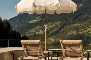 Weißer Sonnenschirm und Stühle auf einem Deck