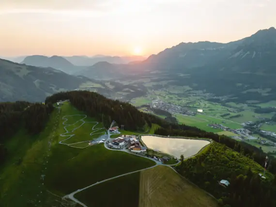 Luftansicht der Landschaft von Kitzbühel mit einem großen See und umliegenden Häusern und einem Dorf im Tal. 