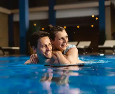Mann und Frau lächeln im Schwimmbecken.