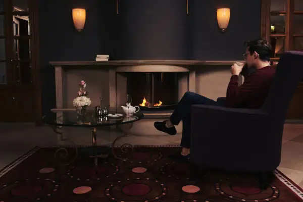 Ein Mann sitzt in einem Stuhl und trinkt aus einer Tasse.