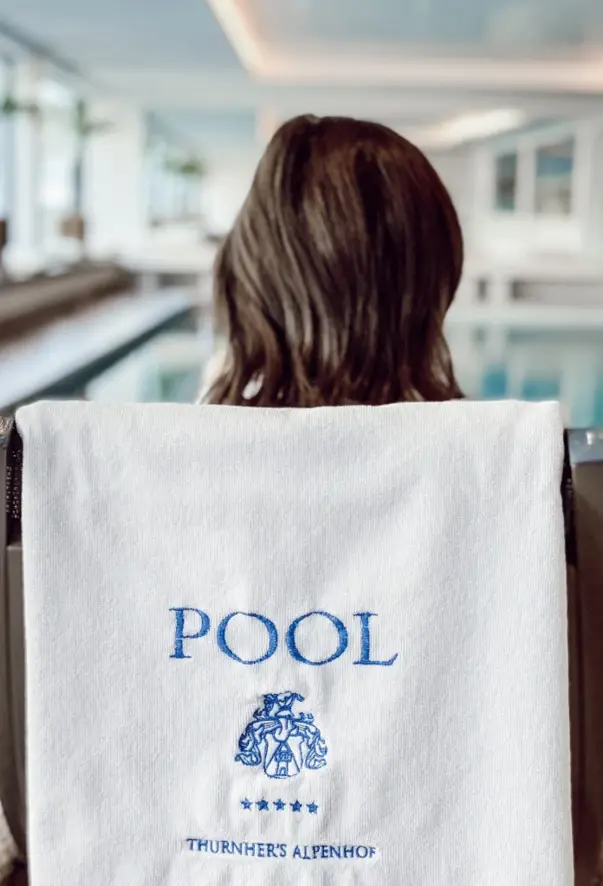 Eine Frau liegt auf einer Liege im SPA und über die Rückenlehne hängt ein Handtuch mit einer blauen Aufschrift „Pool“ und „Thurnher’s SPA“.