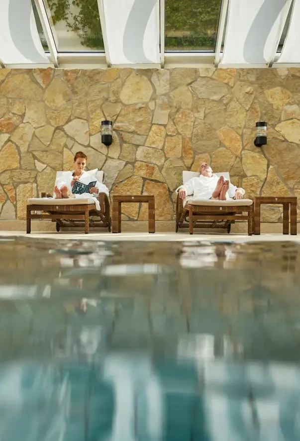 Ein Mann und eine Frau sitzen auf Stühlen neben einem Schwimmbecken.