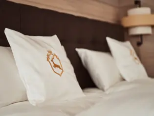 Ein Bett mit Kissen und einem Hirschlogo.