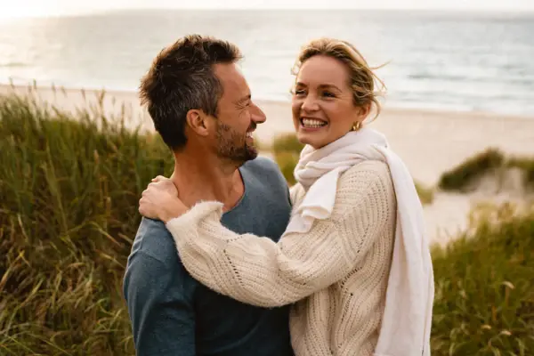 Mann und Frau umarmen sich am Strand.