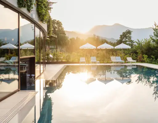 Ein Pool mit Liegestühlen und Sonnenschirmen vor einem Haus.