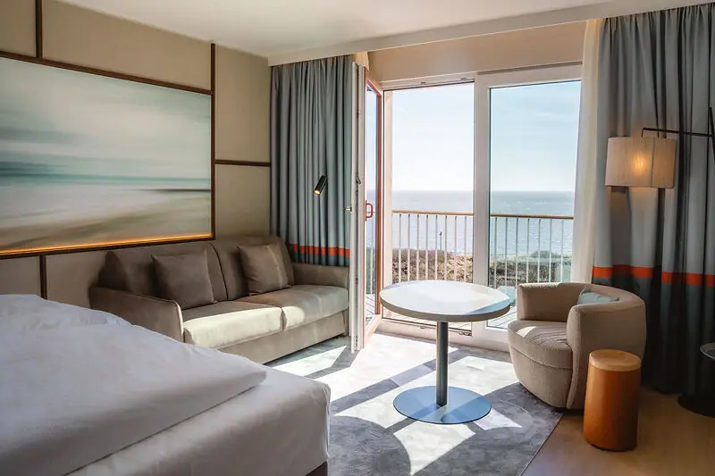 Hotelzimmer mit Bett, Tisch und Stühlen.