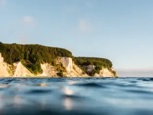 Blick auf eine Wasserfläche mit Klippen und Bäumen.