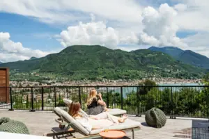 Zwei Frauen sitzen auf einem Deck mit Blick auf ein Gewässer.