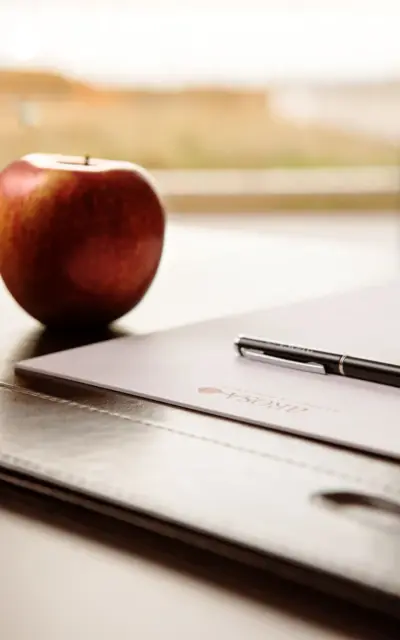 Ein Stift liegt neben einem Apfel auf einem Blatt Papier.