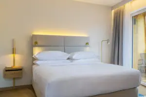 Schlafbereich Ein Bett in einem Zimmer mit eleganter Bettwäsche und Kissen.