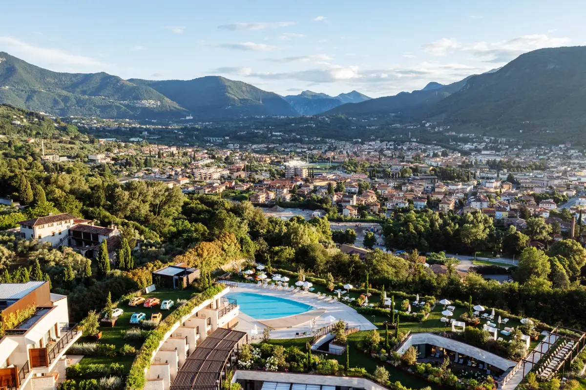 Panoramablick auf die Hotelanlage Luftaufnahme des A-ROSA Gardasee mit terrassenförmiger Poollandschaft und Blick auf die umliegende Landschaft bei Salò.