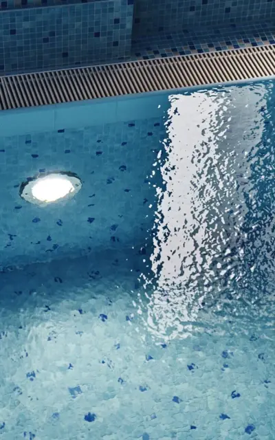 The small blue tiles of the pool can be seen through the gentle waves of the indoor pool. 