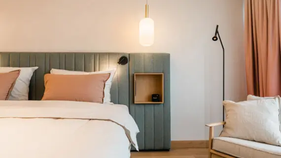 Elegantly designed hotel bedroom featuring a plush bed with a headboard and a bedside lamp.