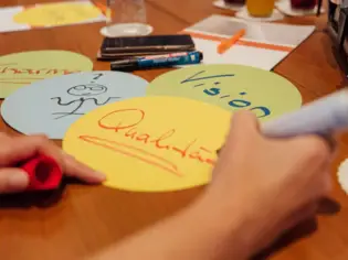 Person schreibt mit einem Stift auf einem runden Papier.