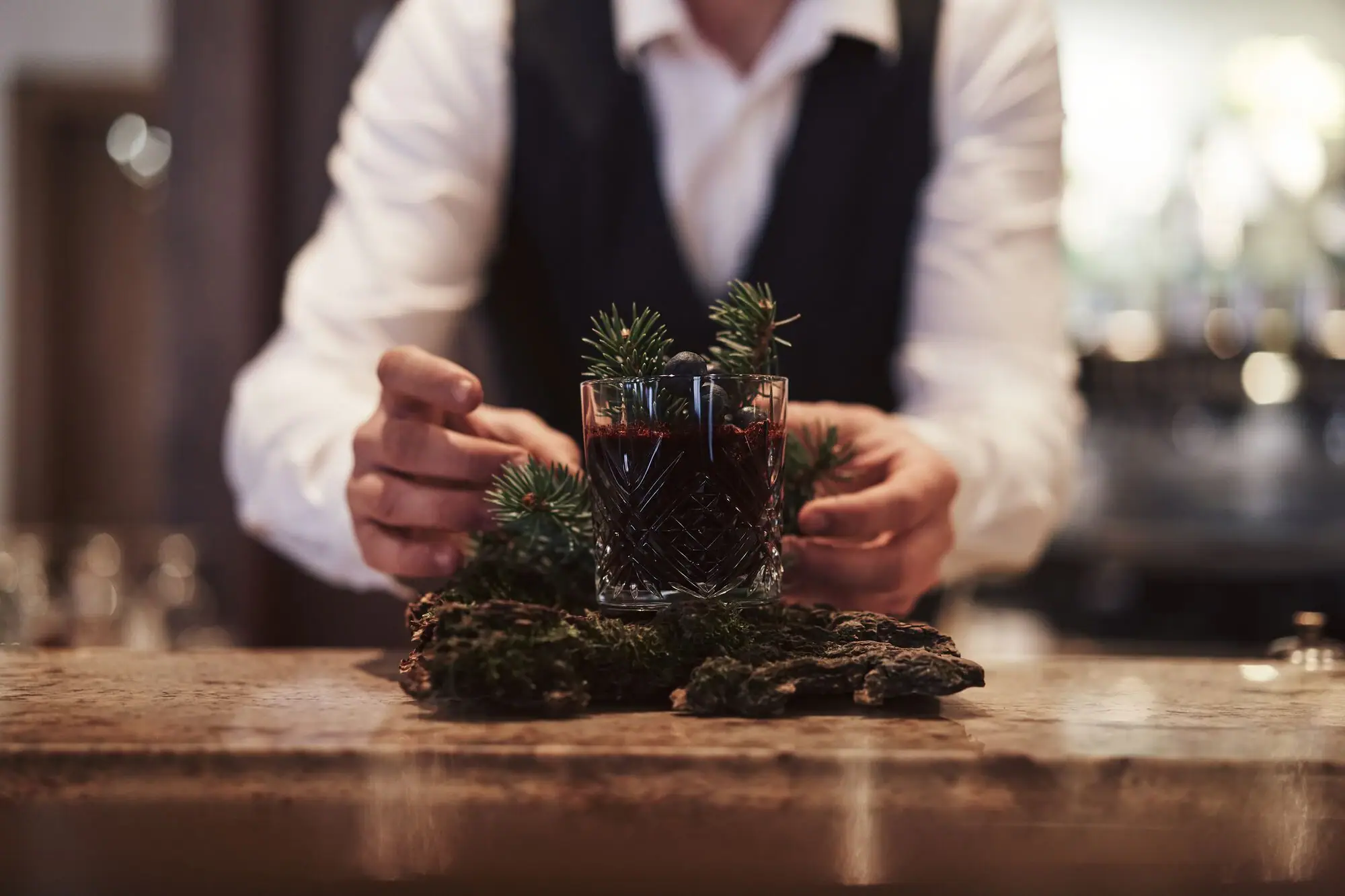 Signature Cocktail: Forest Flair. Eine Person hält ein Glas mit einem Getränk.