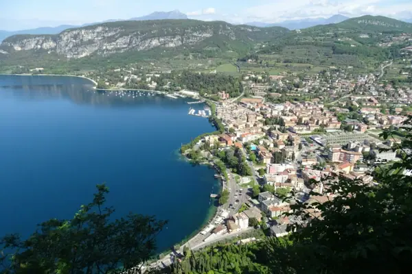 Stadt am Ufer eines Gewässers aus der Vogelperspektive mit Bergen im Hintergrund.