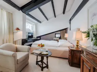 Ein Hotelzimmer mit einem großen Bett, einem Sessel und gemütlicher Dekoration.