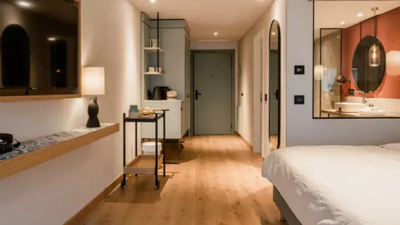 Bedroom with wood flooring, a bed, and a mirror on the wall.