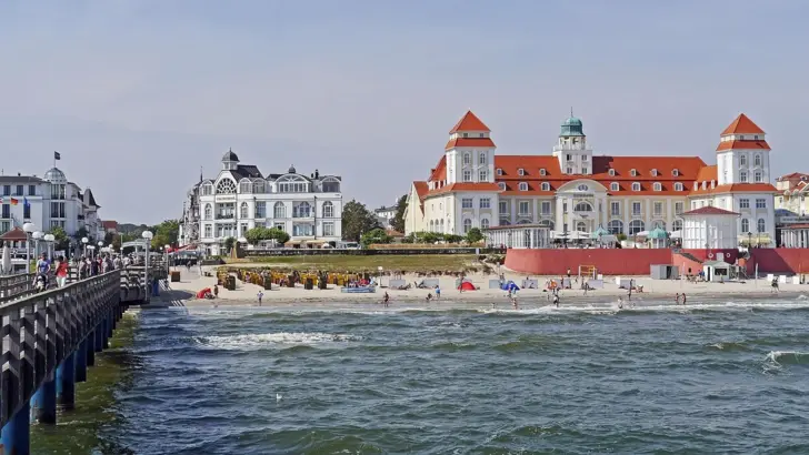 Strand mit Gebäuden und einem Gewässer im Hintergrund