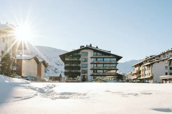 Der kleine Ort Zürs am Arlberg in der Abenddämmerung aus der Vogelperspektive. Die Häuser und Straßen sind beleuchtet.