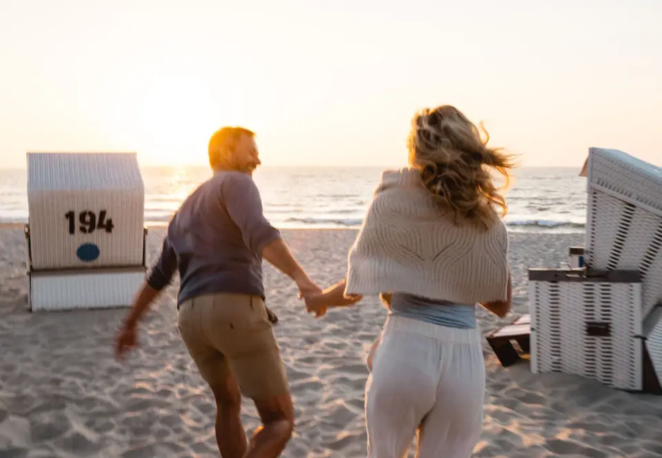 Ein Mann und eine Frau laufen an einem Strand.