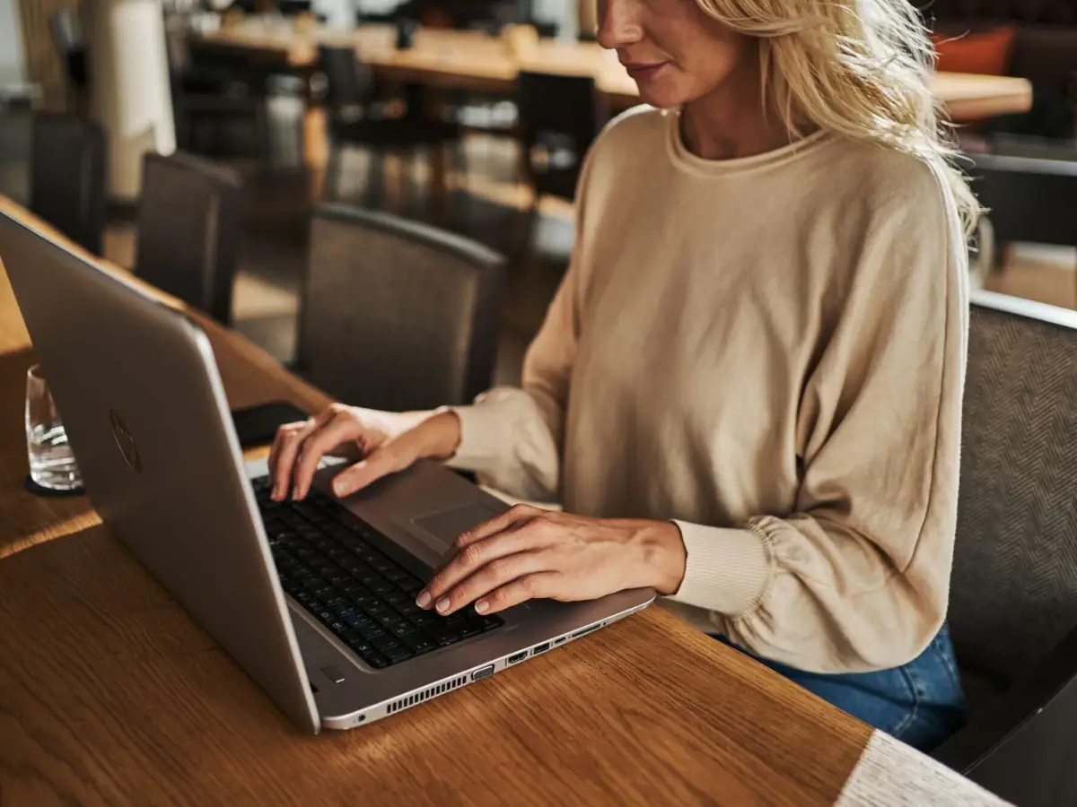 Eine Frau sitzt an einem Tisch und benutzt einen Laptop.