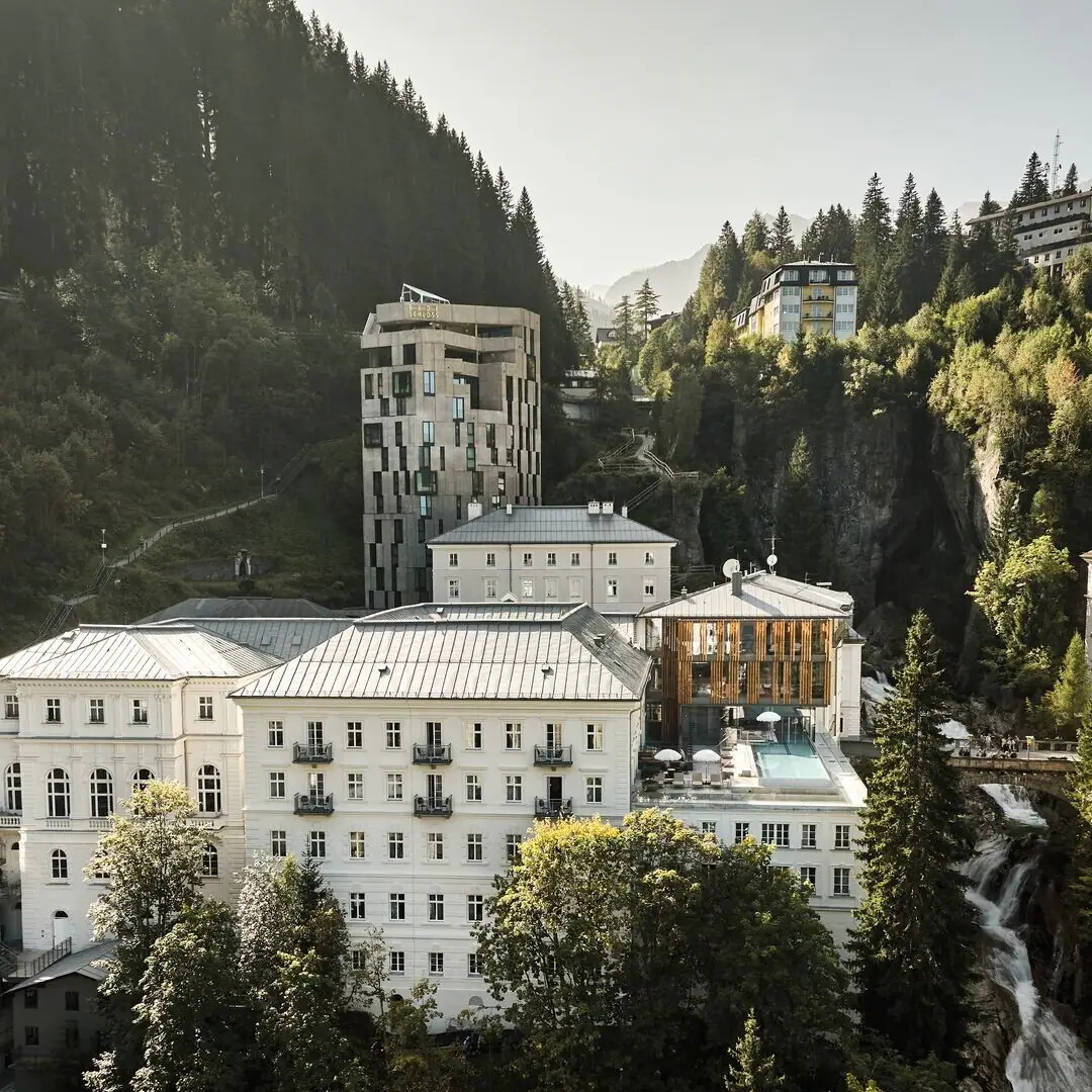 Eine Gruppe von Gebäuden mit Bäumen und Bergen im Hintergrund.