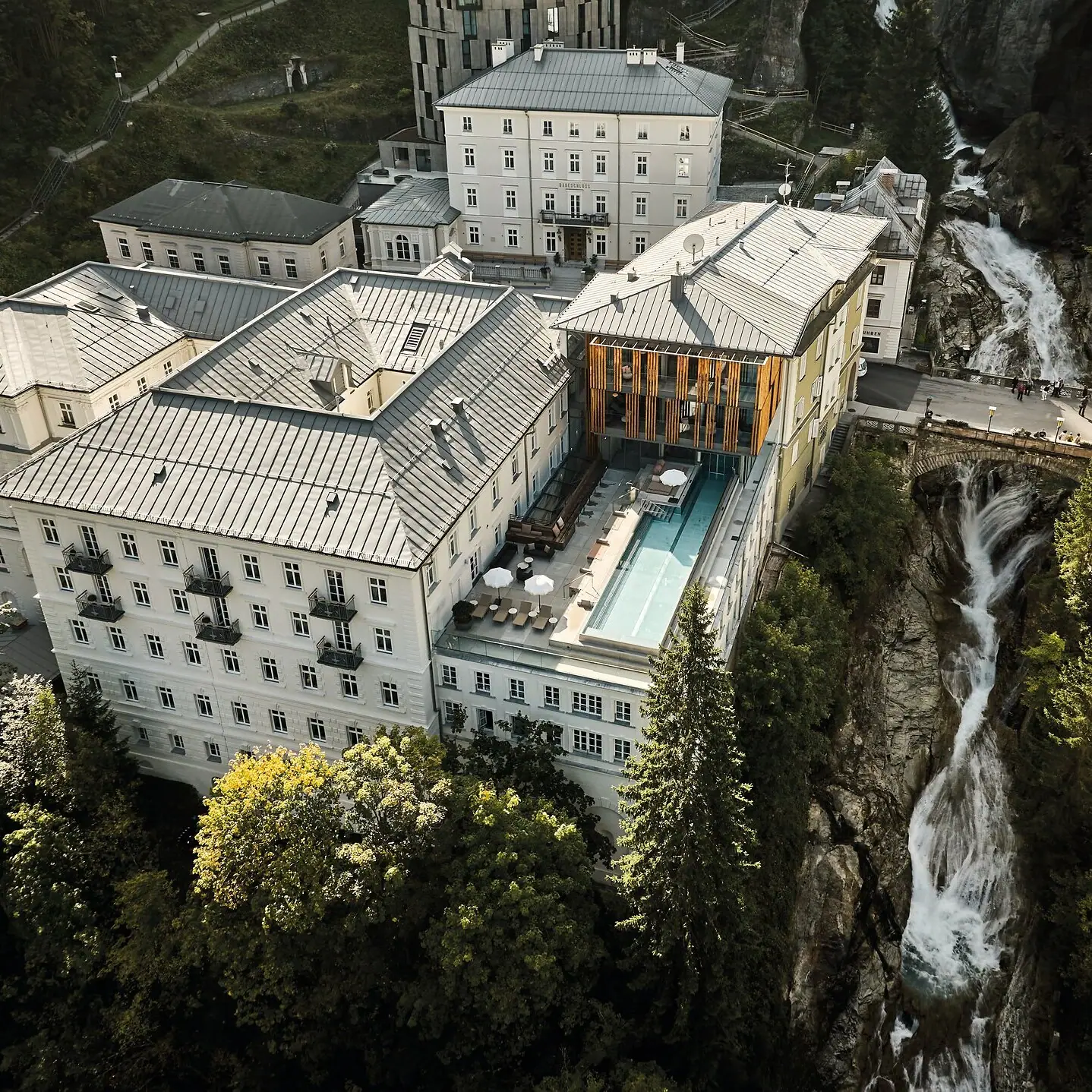 Ein Gebäude mit einem Pool und einem Wasserfall im Freien, umgeben von Bäumen.