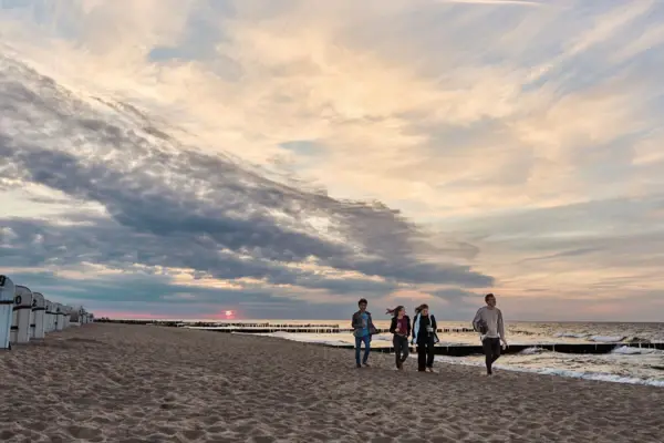 Gruppe von Personen beim Spaziergang am Strand.