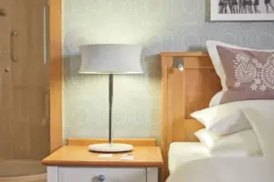 Lampe auf einem Nachttisch neben einem Bett im Schlafzimmer.