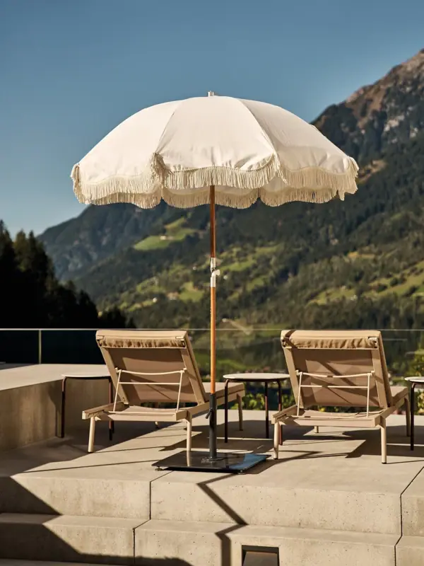 Weiße Sonnenschirme und Stühle auf einer Terrasse.