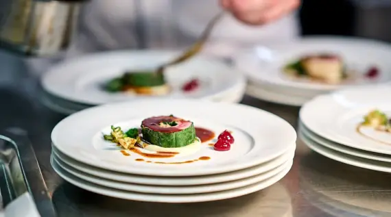 A stack of plates with various dishes on them, including garnishes and cutlery.